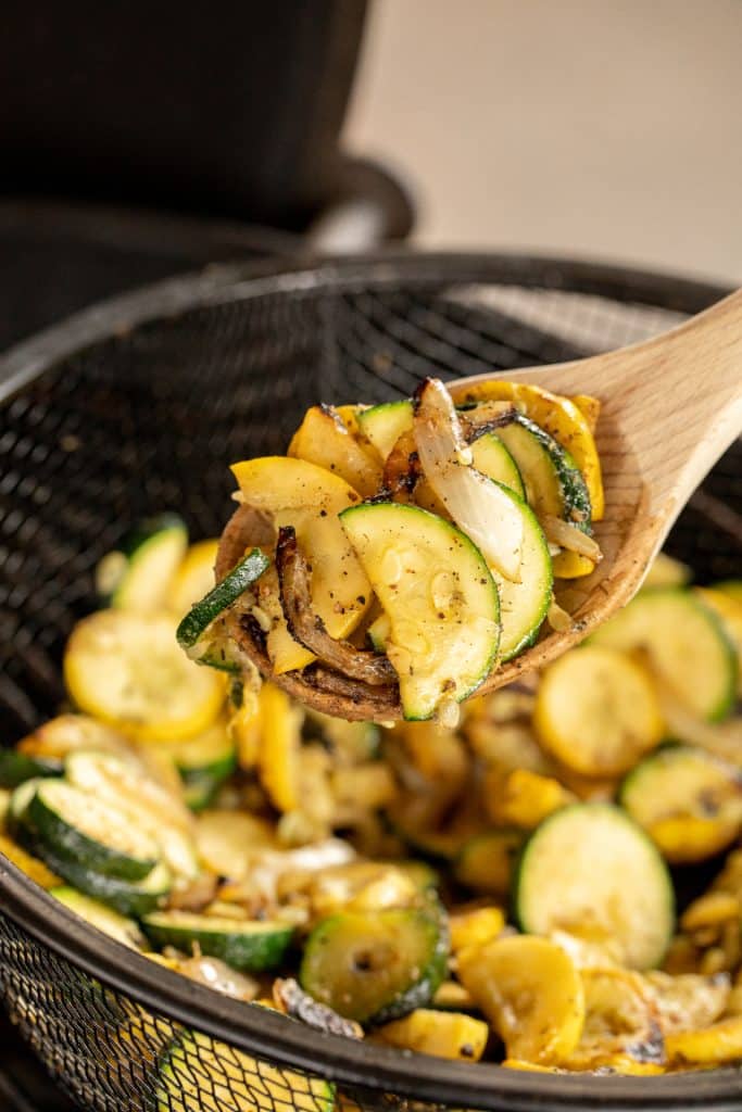 Grilled zucchini and squash on a wooden spoon.