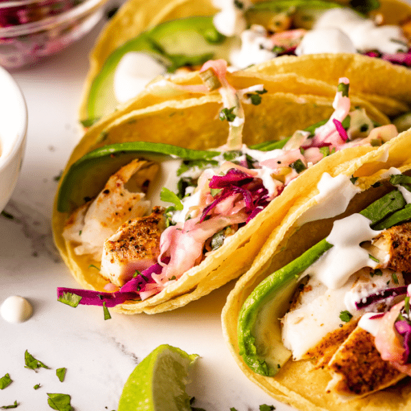 Grilled fish tacos on a white serving dish.