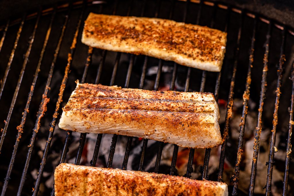 Three seasoned fish fillets on the grill.