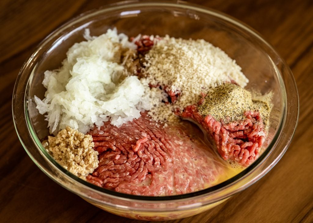 Ingredients for meatloaf in a large glass bowl.