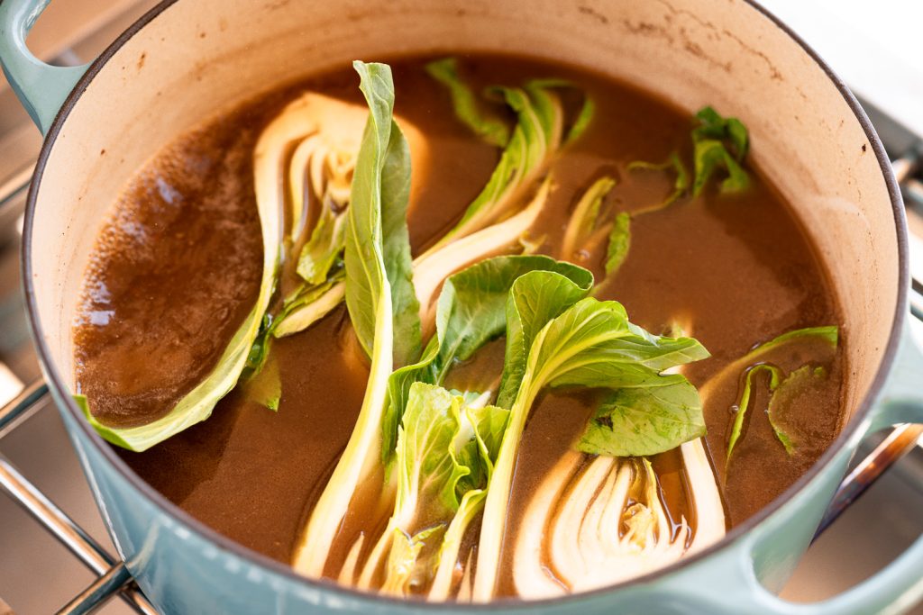 Bok choy in a pot with beef broth.