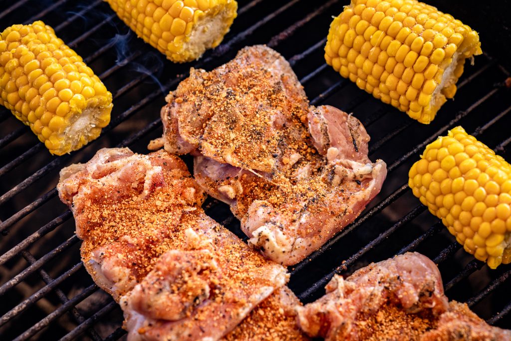 Chicken thighs and cobs of corn on the grill.