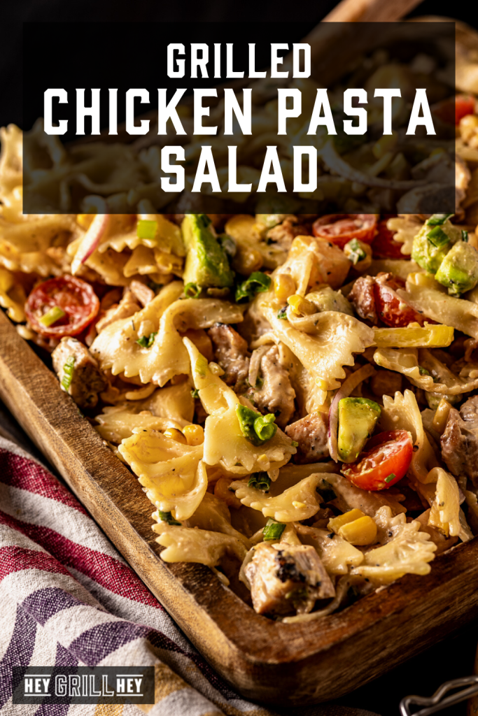 Grilled chicken pasta salad in a wooden bowl with text overlay - Grilled Chicken Pasta Salad.