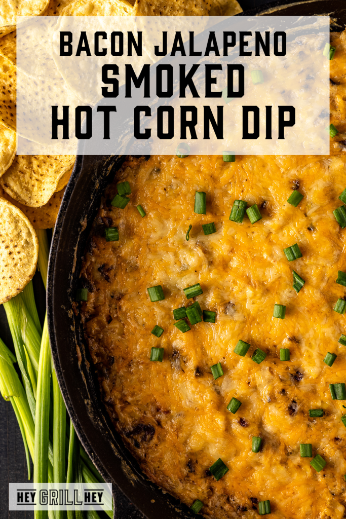 Hot corn dip in a cast iron skillet with text overlay - Bacon Jalapeno Smoked Hot Corn Dip.