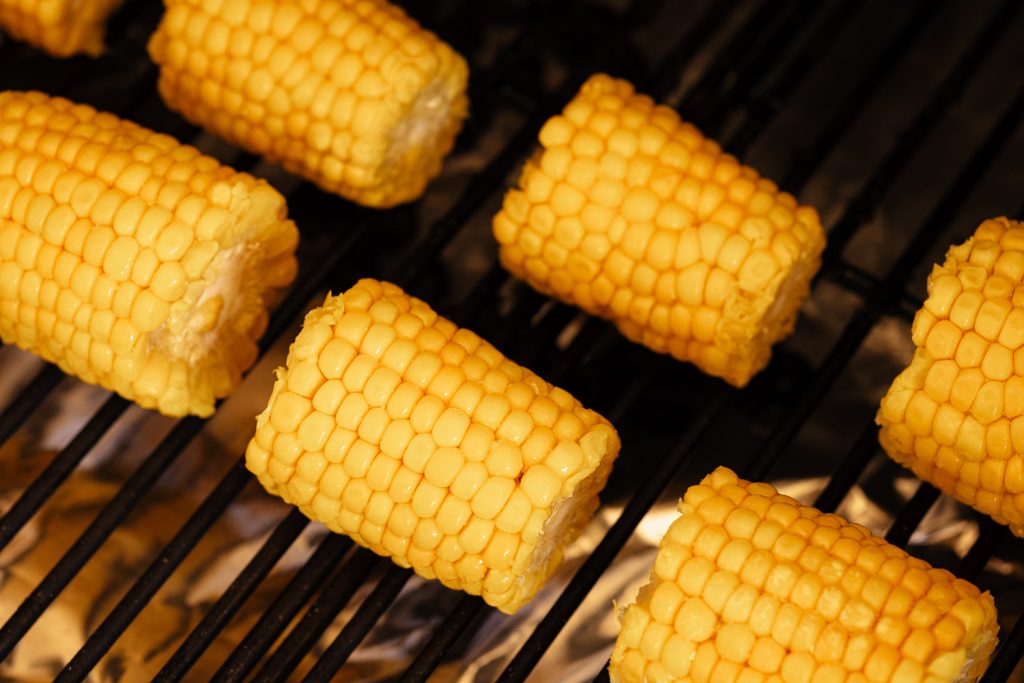 Corn on the cob on the grill grates of a smoker.