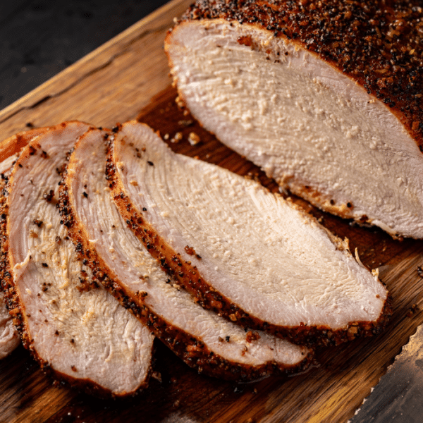 Sliced BBQ turkey breast on a wooden cutting board.