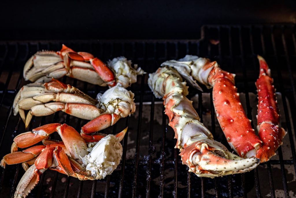 Crab legs on the grill grates of a smoker.