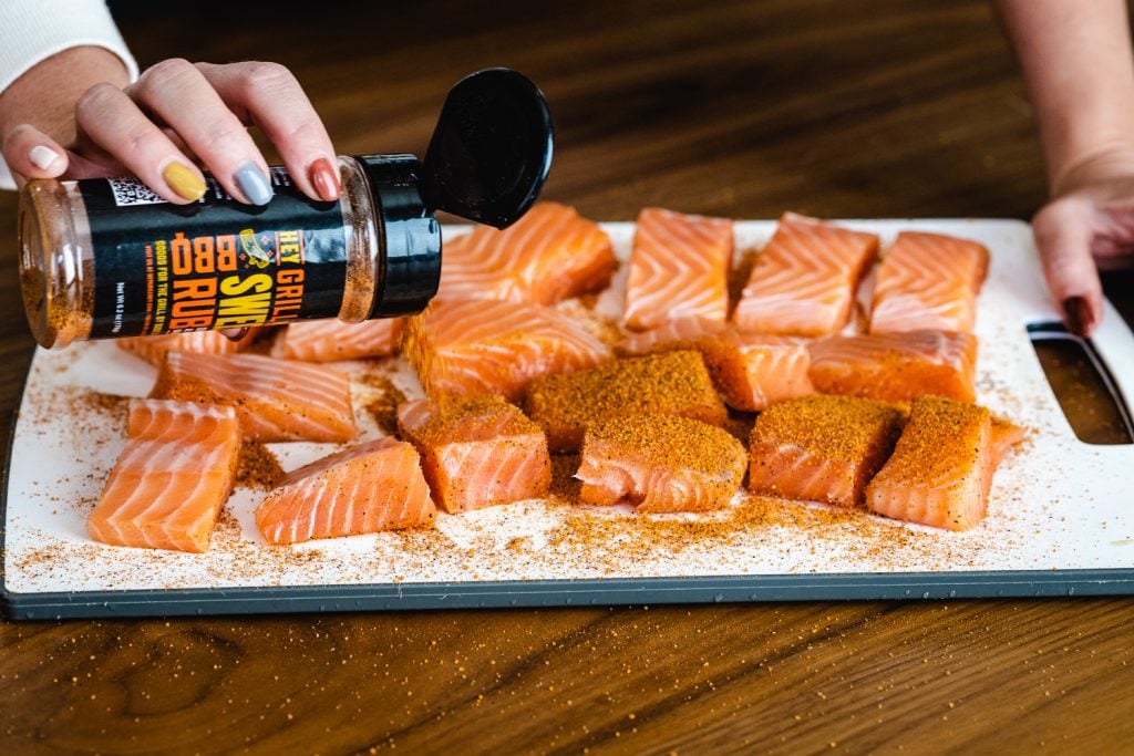 Cubed salmon being seasoned with Hey Grill Hey Sweet Rub.