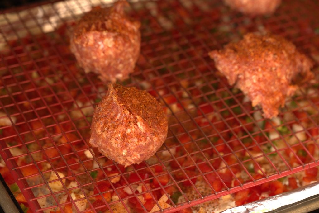 Meatballs on a baking rack above meatballs.