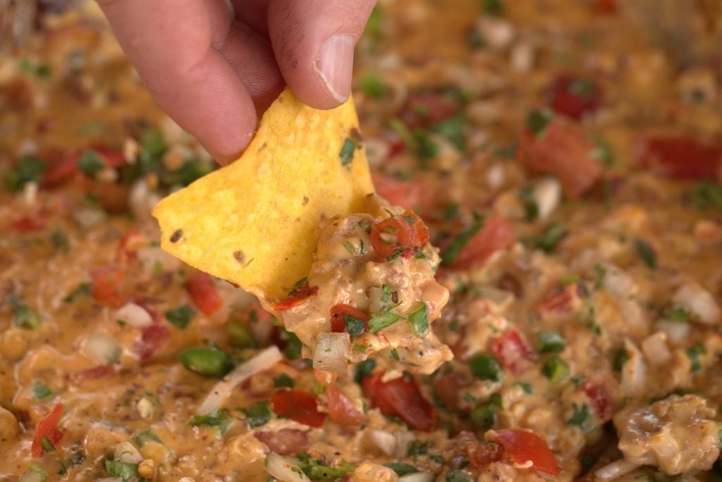 Corn tortilla chip dipped in smoked queso.