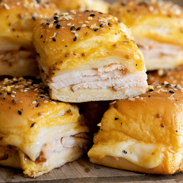 Pile of turkey sliders on a wooden serving board.