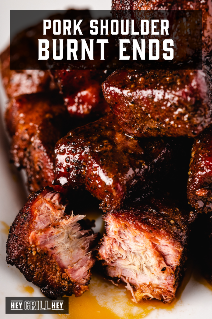 Pile of pork shoulder burnt ends on a white plate with text overlay - Pork Shoulder Burnt Ends.