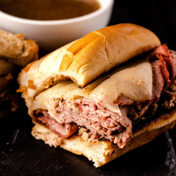 Smoked French dip sandwich next to a bowl of au jus.