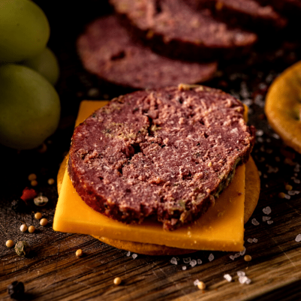 Slice of smoked summer sausage on cheese and crackers.