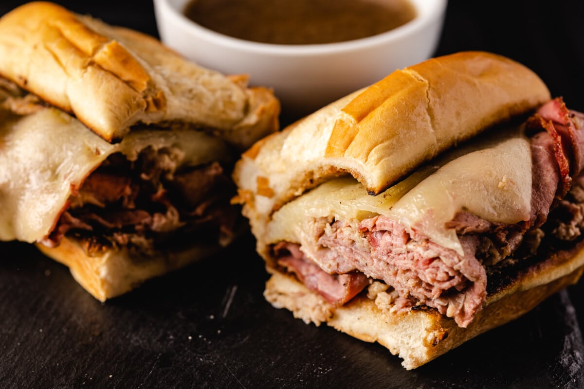 Smoked French dip sandwich next to a bowl of au jus.
