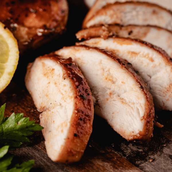 Chicken breast sliced and spread out on a wooden cutting board.