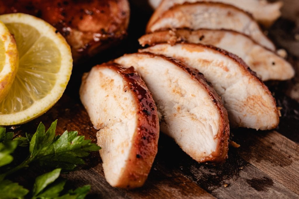 Chicken breast sliced and spread out on a wooden cutting board.