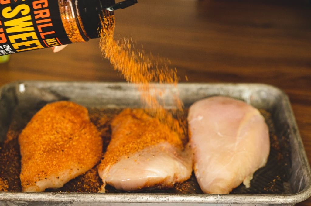 Chicken breasts being seasoned with Hey Grill Hey Sweet Rub.