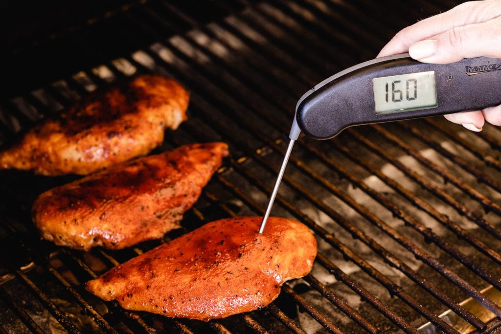 Chicken breast on the grill reading a temperature of 160 degrees F with an instant-read thermometer.