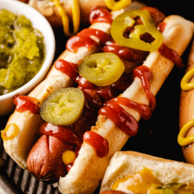 Smoked hot dogs drizzled with ketchup and topped with sliced jalapenos.