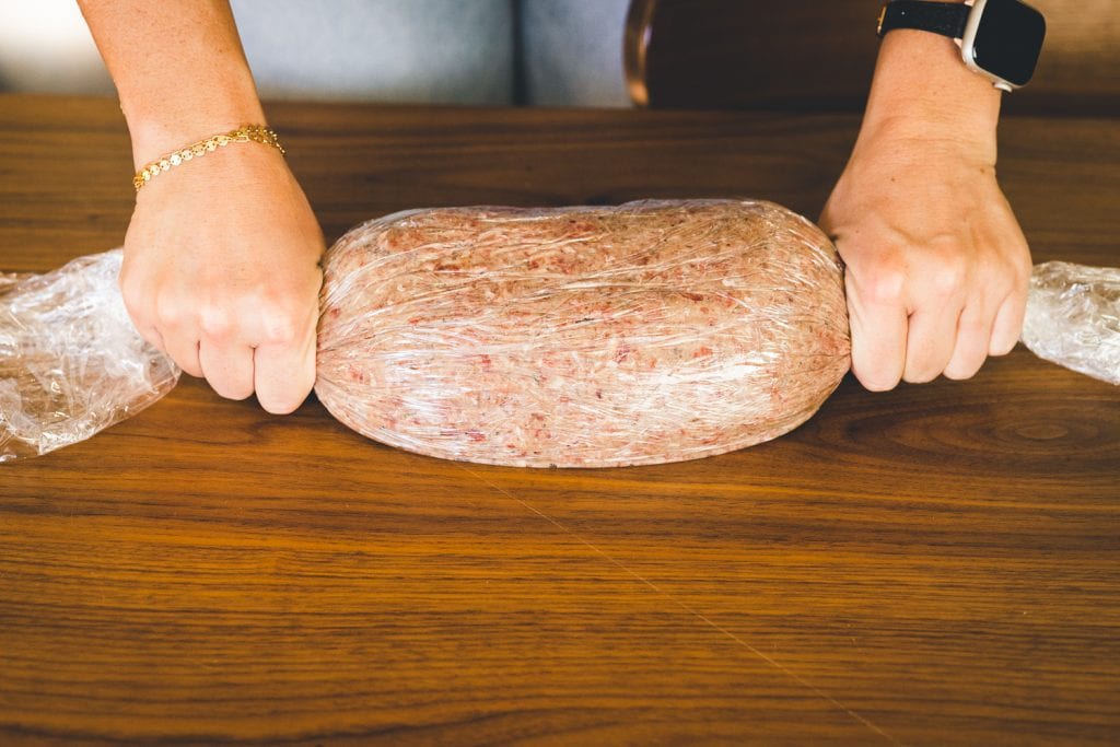 Gyro meat being formed into a log using plastic wrap.