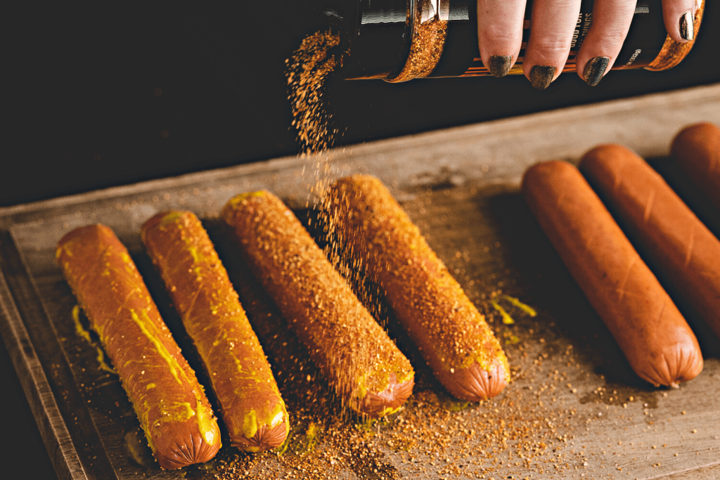 Hot dogs being seasoned with Hey Grill Hey Sweet Rub.