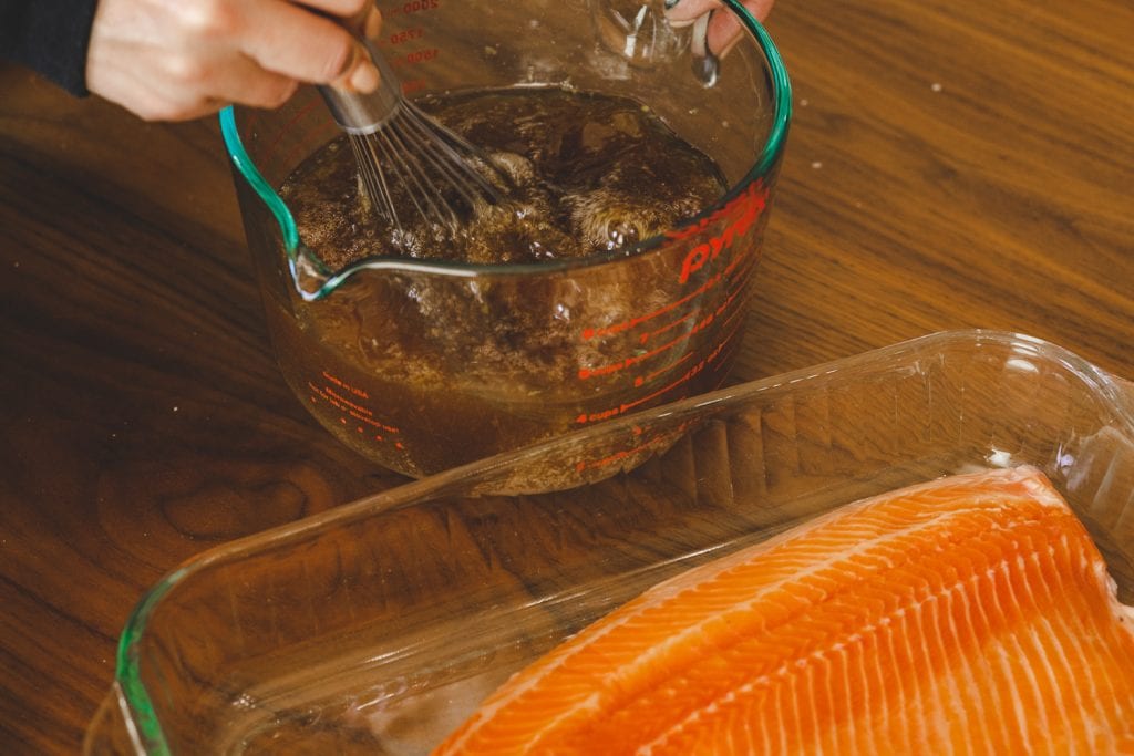 Salmon brine being whisked in a large glass bowl.