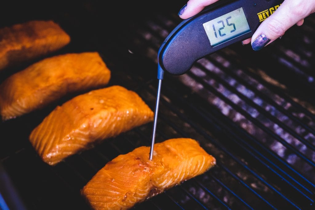 Teriyaki salmon filets on the grill reading a temperature of 125 degrees F.