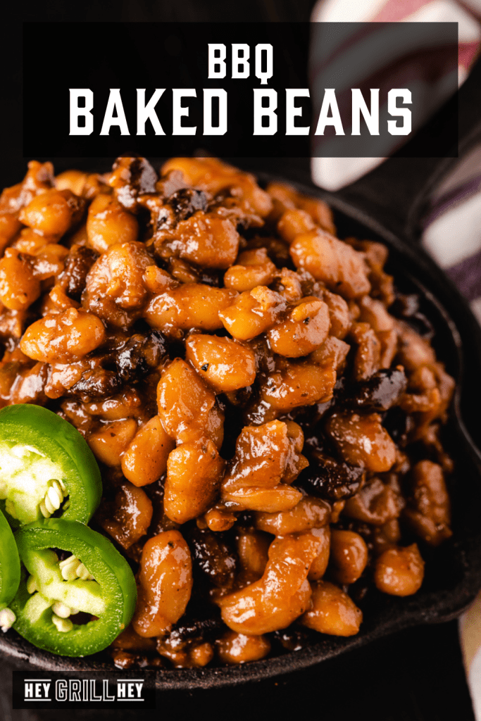 BBQ baked beans in a cast iron skillet with text overlay - BBQ Baked Beans.