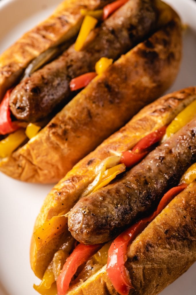 Grilled Italian sausage in buns and topped with peppers.