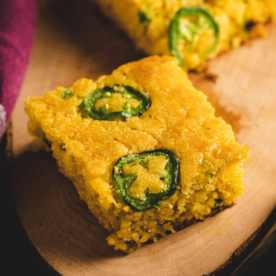 Square of jalapeno cheddar cornbread on a serving dish.