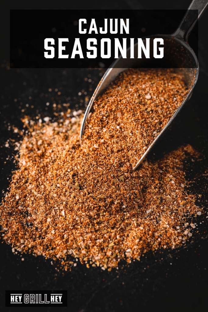 Scoop of cajun seasoning with text overlay - Cajun Seasoning.