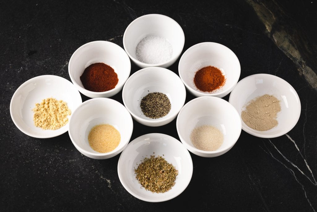 Ingredients for Cajun seasoning in individual small white bowls.