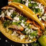 Grilled chicken tacos loaded with cilantro and cheese.