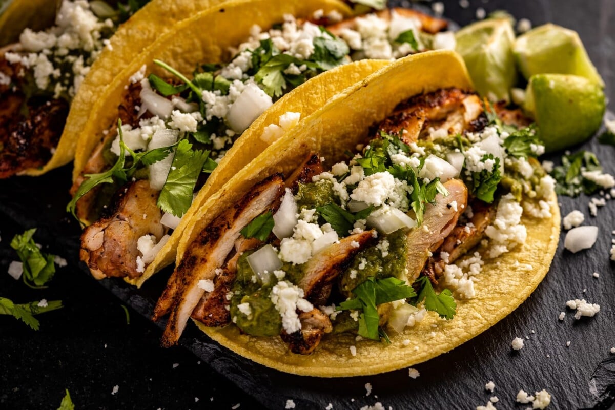 Grilled chicken tacos loaded with cilantro and cheese.