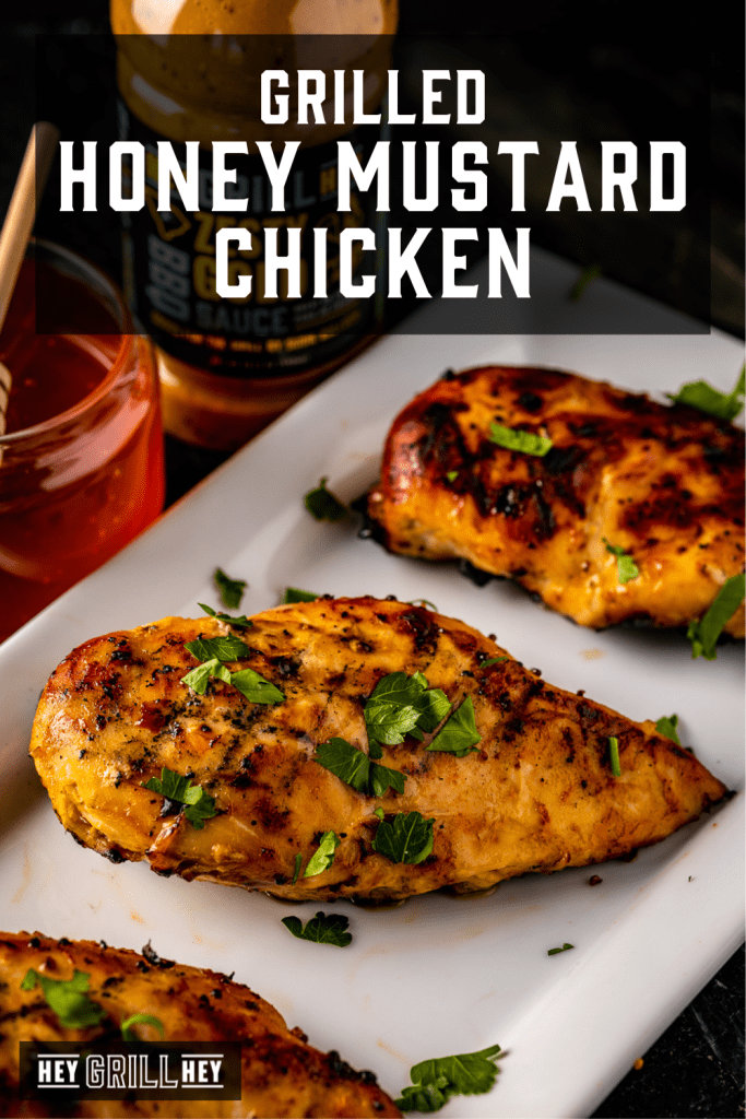 Grilled honey mustard chicken breasts on a white serving platter with text overlay - Grilled Honey Mustard Chicken.
