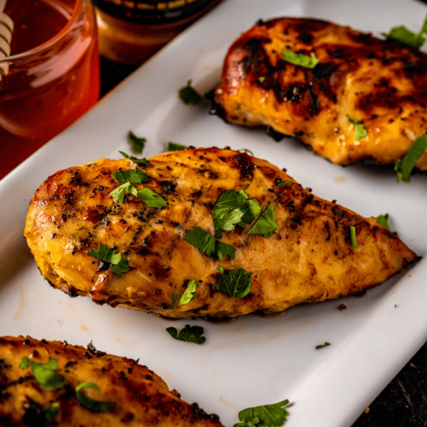 Grilled honey butter chicken breasts on a white serving platter.