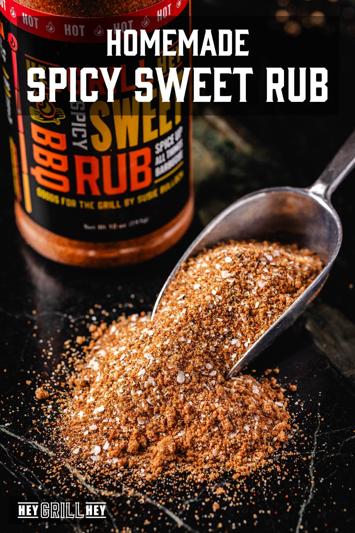 A seasoning scoop overflowing with spice onto a counter, in front of a jar. The text overlay reads "Homemade Spicy Sweet Rub" at the top, and "Hey Grill Hey" at the bottom.