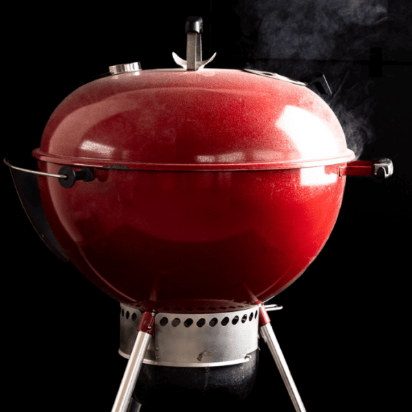 Smoke billowing out from a red charcoal grill with text overlay.