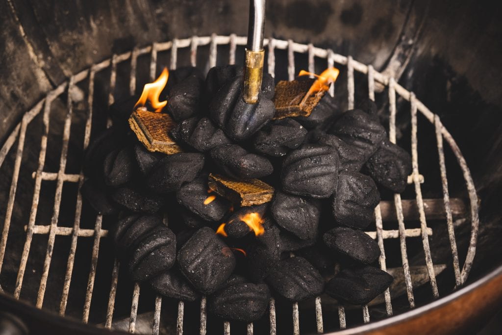 Charcoal in a grill with fire underneath.