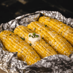 Grilled corn on the cob in a bed of foil.