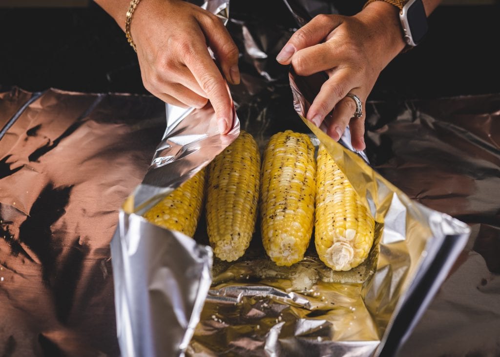 Corn on the cob being wrapped in foil.