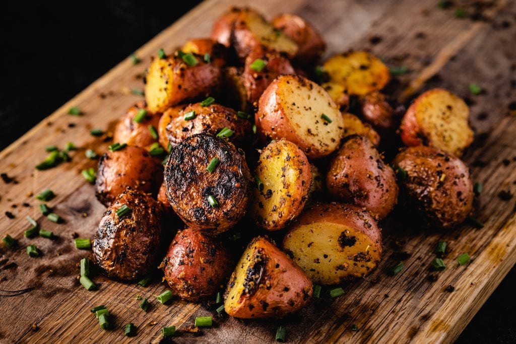 Pile of grilled red potatoes on a cutting board.