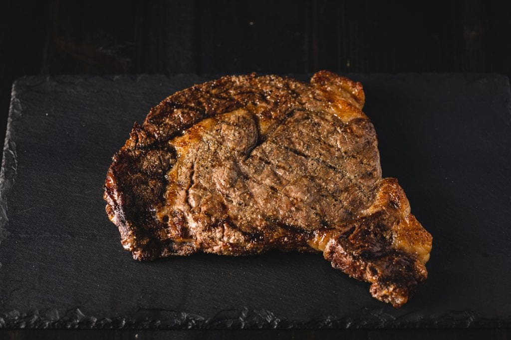 Gas grilled ribeye steak on a cutting board.