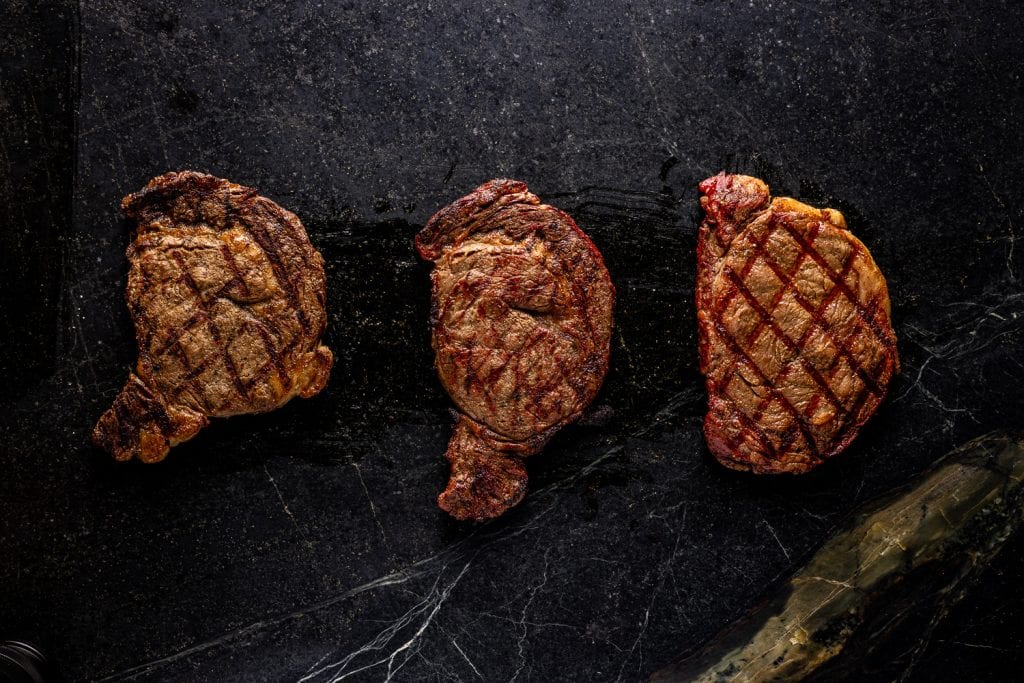 Three gas grilled steaks on a serving platter.