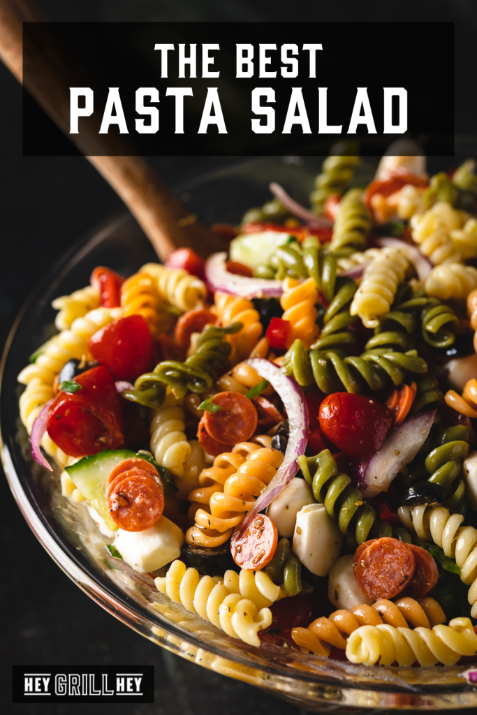 Pasta salad in a glass serving bowl with text overlay - The Best Pasta Salad.