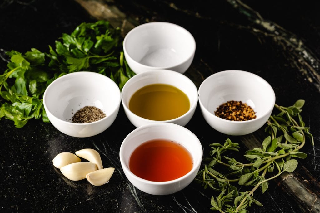 Ingredients for chimichurri in individual bowls.