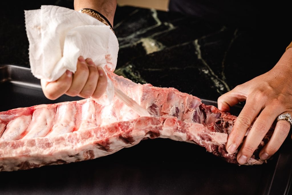 Membrane being removed from the backside of baby back ribs.