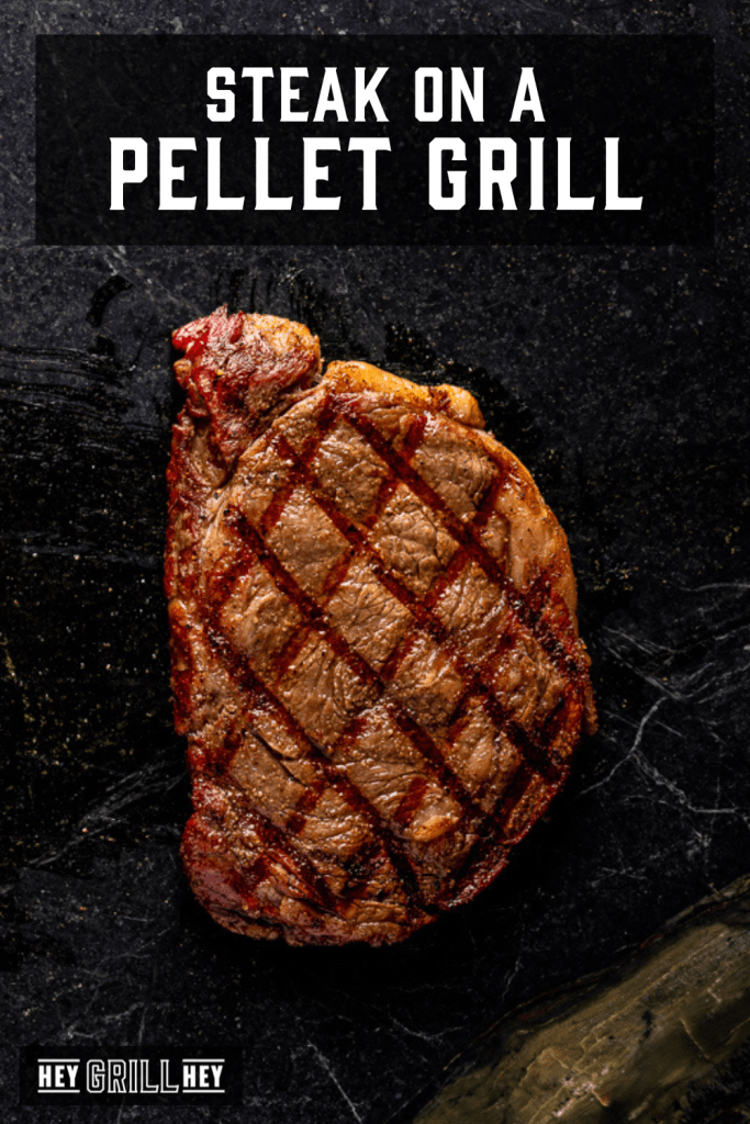 Steak on a dark serving platter with text overlay - Steak on a Pellet Grill.