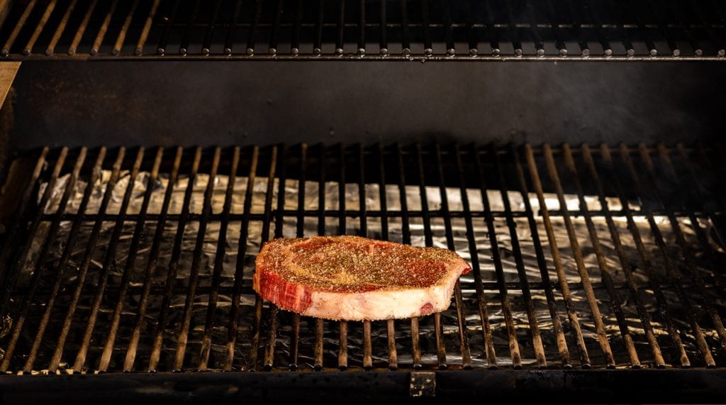 Seasoned ribeye steak on a pellet grill.
